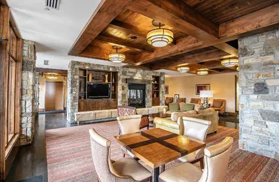 a living room with a table and a stone wall at Ski Trails 4119 by East West Hospitality in Truckee