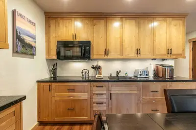 a kitchen with wooden cabinets and a microwave at Ski Trails 4119 by East West Hospitality in Truckee