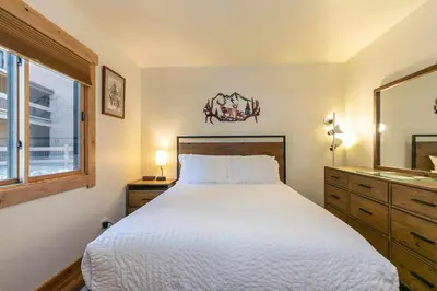 a bedroom with a large white bed and a sink at Ski Trails 4119 by East West Hospitality in Truckee