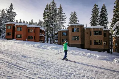 a person on skis in the snow in front of condos at Ski Trails 4119 by East West Hospitality in Truckee