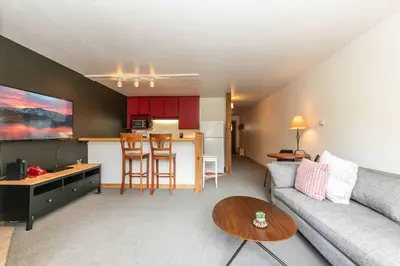 a living room with a couch and a kitchen with red cabinets at Ski Trails 4099 by East West Hospitality in Truckee
