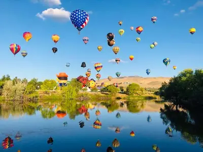 a bunch of hot air balloons flying over a lake at 2BR Getaway Pool Gym Basketball Court & Theater Access in Reno