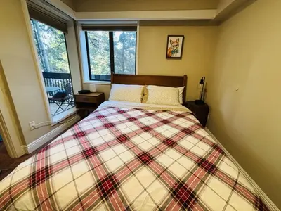 a bedroom with a bed with a plaid blanket and a window at Knotty & Nice in Incline Village