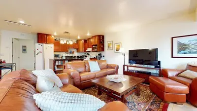 a living room with brown leather furniture and a kitchen at Lakeview Villas #26 condo in Mammoth Lakes