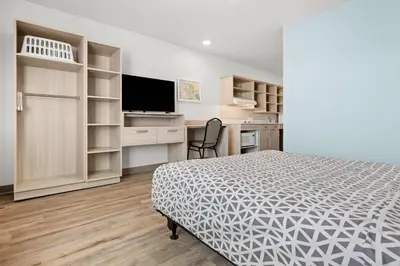 a bedroom with a bed and a desk and a television at WoodSpring Suites Ceres - Modesto in Ceres