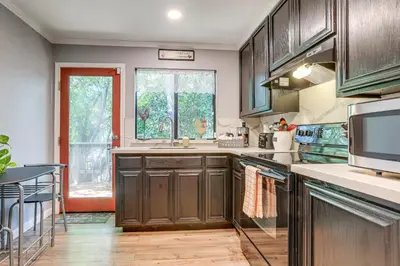 a kitchen with wooden cabinets and a large window at Downtown Fair Oaks Home about 15 Mi to Sacramento! in Fair Oaks
