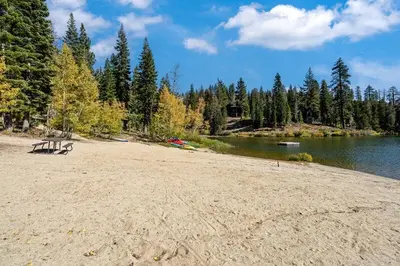 a bench sitting on a sandy beach next to a lake at Cozy Corner Tamarack Condo 19 in Tamarack