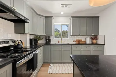a kitchen with gray cabinets and a black counter top at The River House in Three Rivers