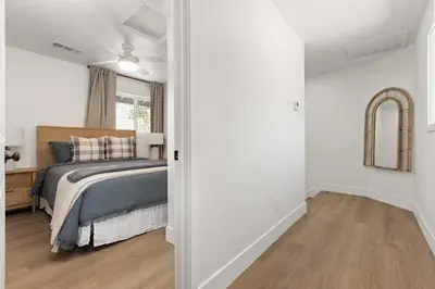 a bedroom with white walls and a bed and a mirror at The River House in Three Rivers