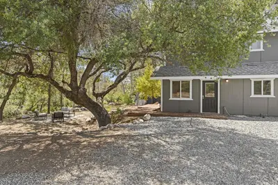 a house with a tree in front of a driveway at The River House in Three Rivers