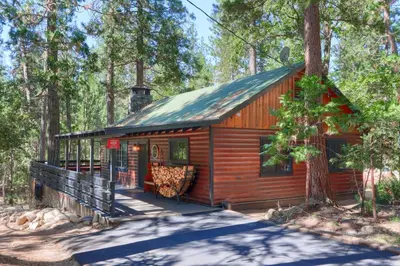 a log cabin in the woods with a porch at 45 The Overlook in Wawona
