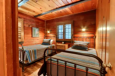 two beds in a room with wooden walls at 45 The Overlook in Wawona