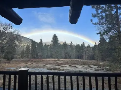 a rainbow in the sky over a field at Peppermint Falls Ranch in Ponderosa