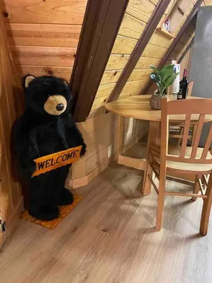 a teddy bear holding a welcome sign next to a table at Cozy Chalet - Hot Tub with Meadow Views - Family & Pets, Fire Pit & BBQ in Arnold