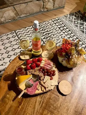 a table with a plate of food and a bottle of wine at Cozy Chalet - Hot Tub with Meadow Views - Family & Pets, Fire Pit & BBQ in Arnold