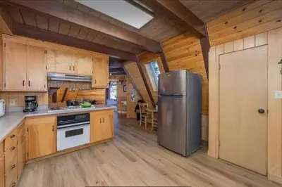 a kitchen with wooden cabinets and a stainless steel refrigerator at Cozy Chalet - Hot Tub with Meadow Views - Family & Pets, Fire Pit & BBQ in Arnold