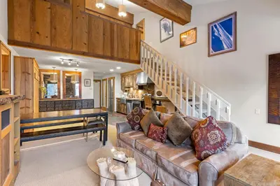 a living room with a couch and a staircase at Palisades Tahoe Lodge Rentals Studio Loft #344 in Olympic Valley