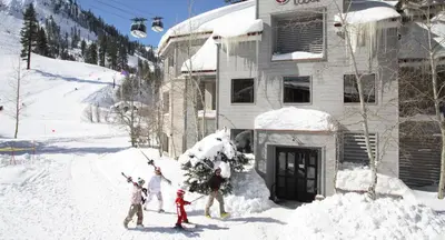 a group of people standing in the snow in front of a house at Palisades Tahoe Lodge Rentals Studio Loft #344 in Olympic Valley
