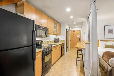a kitchen with a black refrigerator freezer next to a bed at Palisades Tahoe Lodge Rentals Studio Loft #346 in Olympic Valley