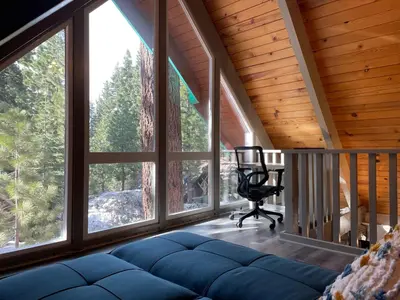 a living room with a chair and large windows at Tahoe Time Cabin in Incline Village