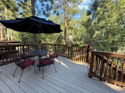 a table and chairs on a deck with an umbrella at Tahoe Time Cabin in Incline Village