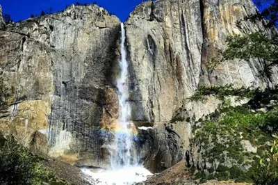 a rainbow in front of a waterfall on a mountain at Above the Green in Groveland