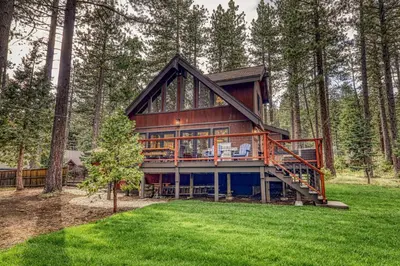 a house in the woods with a wrap around deck at Eclipse Retreat at Tahoe Park - Hot Tub - Fenced Yard & steps to HOA Access in Tahoe City