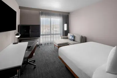 a hotel room with a bed and a couch and a tv at Courtyard by Marriott Reno Sparks in Clark