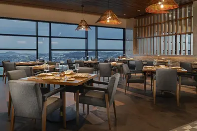 a restaurant with tables and chairs and large windows at Chicken Ranch Casino Resort in Jamestown