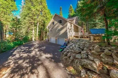 a home with a stone wall and a house at Cabin at the Creek Family Fun Starts Here! in Shaver Lake