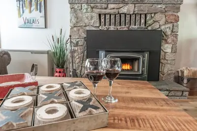 a table with two glasses of wine and a fireplace at Buckeye Bear's Den-AC-Walking Distance to town in Shaver Lake
