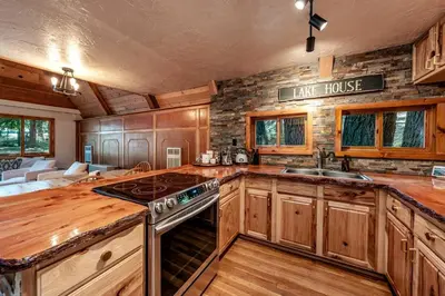 a kitchen with wooden cabinets and a stove top oven at HB Hideaway Boho Treehouse Vibes in the Pines in Shaver Lake