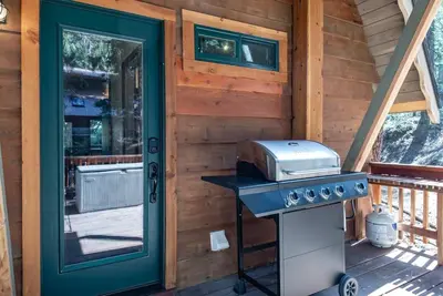 a barbecue on the porch of a cabin at HB Hideaway Boho Treehouse Vibes in the Pines in Shaver Lake