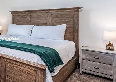 a bedroom with a bed with a wooden headboard and a nightstand at Leopard Lily Lodge Luxe Stays 2 Suites AC in Shaver Lake