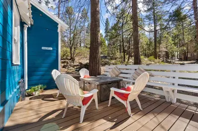 a deck with chairs and a table on a blue house at Tollhouse Cottage Heart of Shaver in Shaver Lake