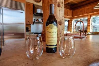 a bottle of wine sitting on a table with two wine glasses at Waterfall Lodge Yellowstone Vibes AC Space in Shaver Lake
