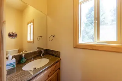 a bathroom with a sink and a mirror and a window at The Restful Rose Fireside Vibes AC Comfort in Shaver Lake
