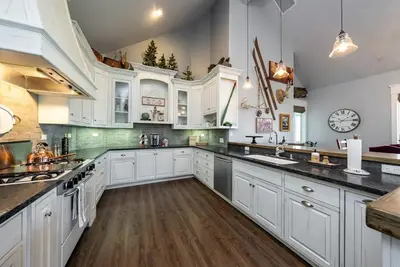 a large kitchen with white cabinets and a clock on the wall at The Great Escape Sunsets Hot Tub Bliss in Shaver Lake