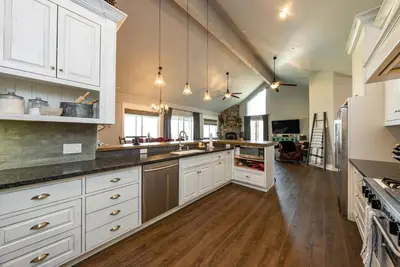 a large kitchen with white cabinets and wooden floors at The Great Escape Sunsets Hot Tub Bliss in Shaver Lake