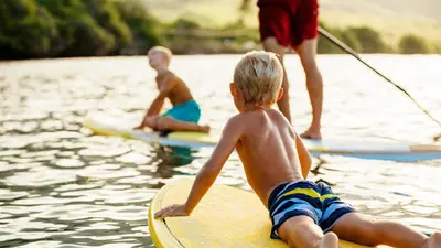 two young boys laying on a surfboard in the water at The Sparrows Nest Cozy Charm Fire Pit Fun in Shaver Lake