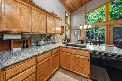a kitchen with wooden cabinets and a black dishwasher at Shady Pines Smores, Stars & Cozy Nights In in Shaver Lake