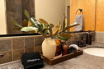 a bathroom counter with a vase with a plant in it at Shady Pines Smores, Stars & Cozy Nights In in Shaver Lake