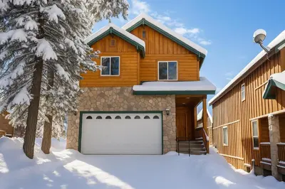 a wooden house with a garage in the snow at Sierra Pines Villa Deck Jetted Tub Game Rm in Shaver Lake