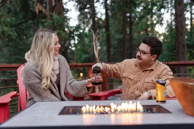 a man and woman sitting at a table with a glass of wine at Mystic Meadow Sweet Cabin Meadow Views in Shaver Lake