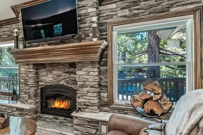 a stone fireplace in a living room with a tv at Lux Western Cabin Pool Table Ping Pong Vibes in Shaver Lake
