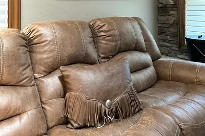 a brown leather couch with a pillow on it at Lux Western Cabin Pool Table Ping Pong Vibes in Shaver Lake