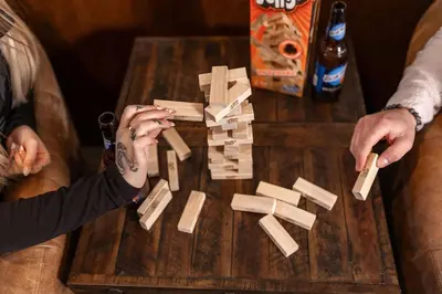 two people playing with wooden dominoes on a table at Lux Western Cabin Pool Table Ping Pong Vibes in Shaver Lake