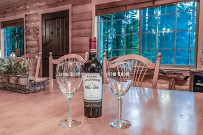 a bottle of wine and two wine glasses on a table at The Stew Cabin Cozy Escape Fireside Memories in Shaver Lake