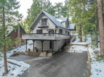 a house in the woods with snow on the ground at Ridgeview Retreat Location Meets Comfort AC! in Shaver Lake