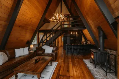 a living room with a couch and a fireplace at Modern Black A-Frame overlooking a Meadow w AC! in Shaver Lake
